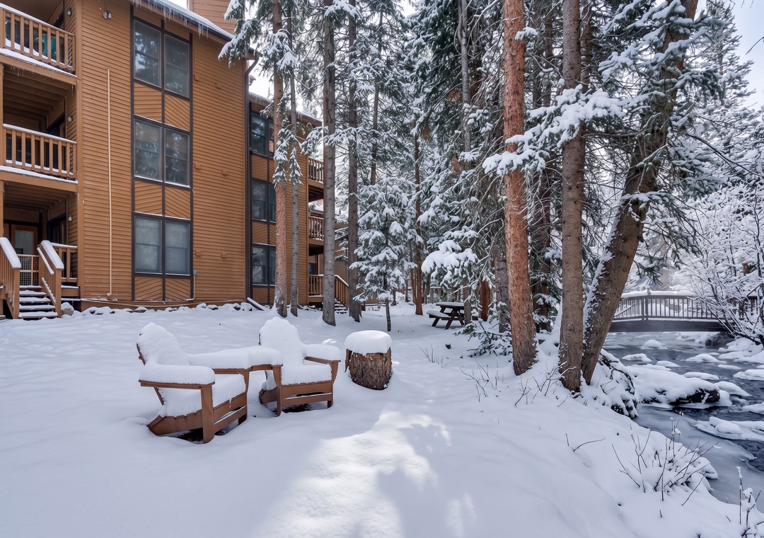 A winter wonderland awaits just outside your door. Fresh powder blankets the towering pines and riverside seating, creating a serene mountain escape perfect for cozy retreats.