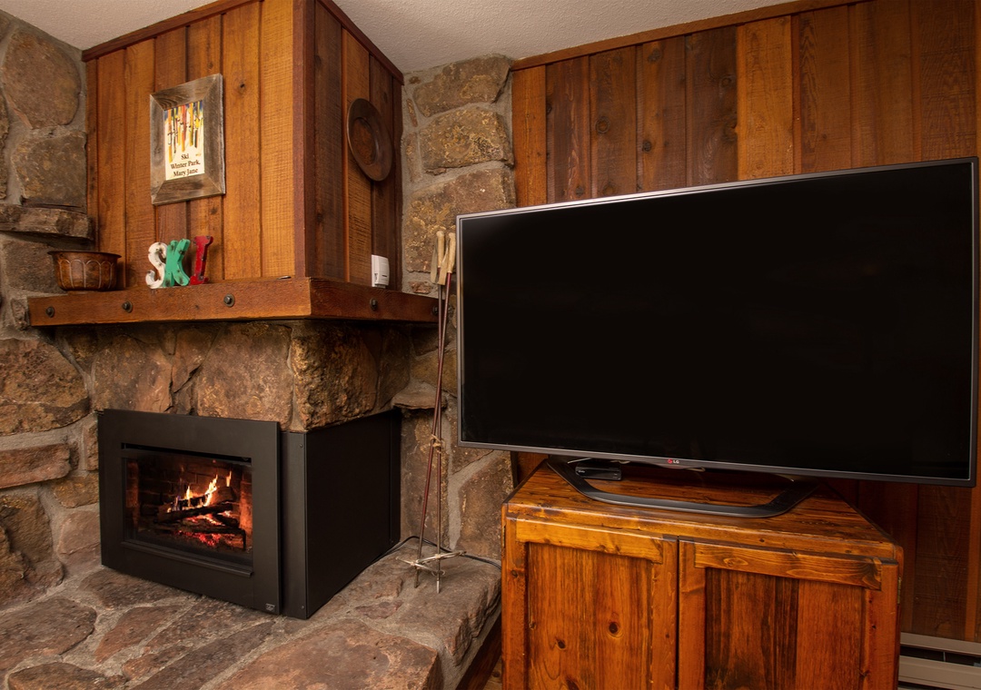 Cozy up by your crackling fireplace while watching your favorite shows on the large flat-screen TV in this rustic living space.