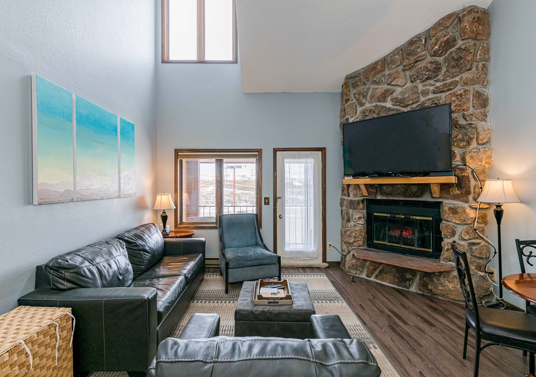 Unwind in your spacious living room at 643 SilverCreek Inn featuring plush leather seating and a cozy stone fireplace perfect for relaxing evenings.