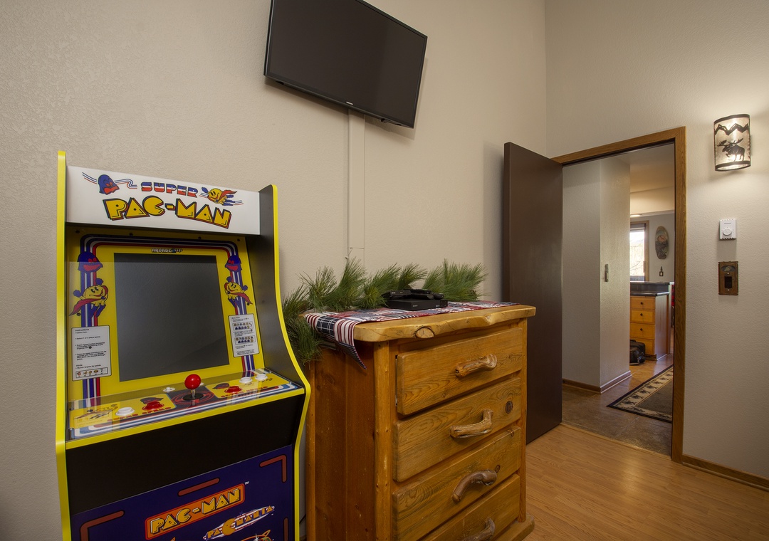 Unwind in your game room with vintage Pac-Man arcade fun, wall-mounted TV for movie nights, and rustic storage for all your belongings.
