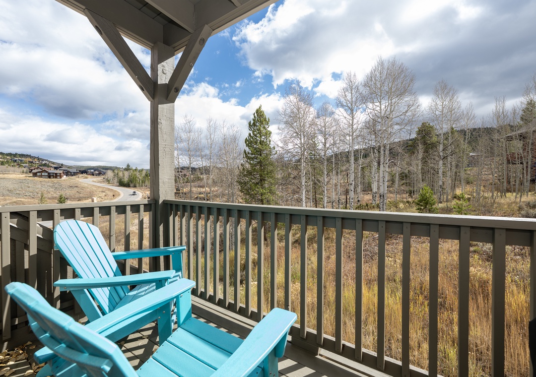 Relax on your private balcony with turquoise Adirondack chairs and sweeping mountain views—your perfect retreat spot when you stay at Kicking Horse Buckskin 3-205.