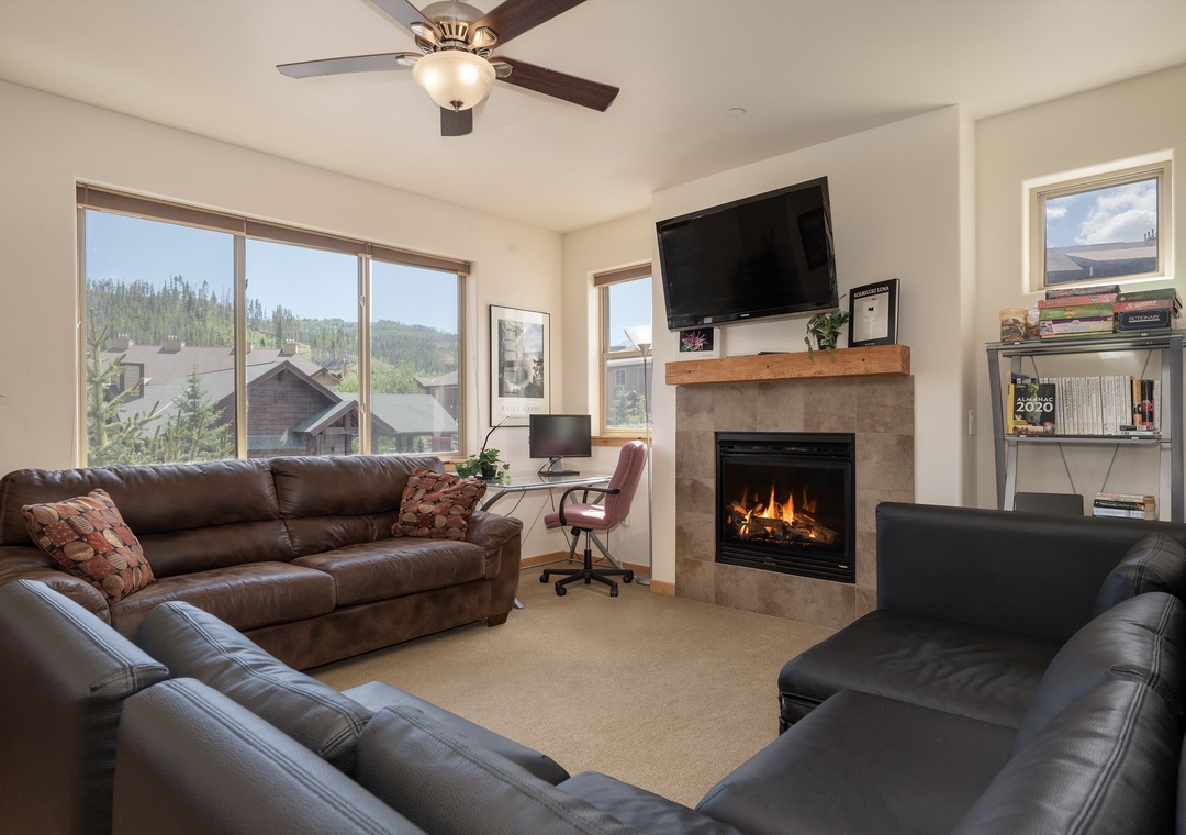 Cozy up in your spacious living room with leather seating, crackling fireplace, and stunning mountain views through expansive windows.