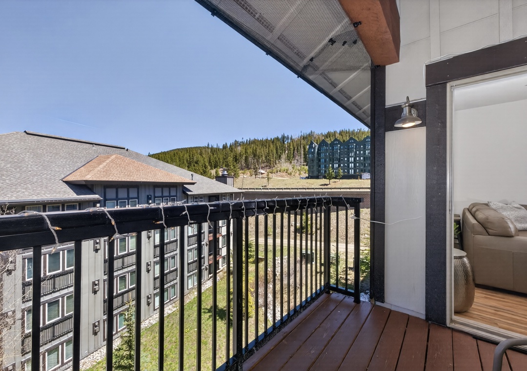 The balcony provides a scenic view of forested hillsides and nearby buildings, blending comfort with natural beauty—perfect for your morning coffee or evening unwind.