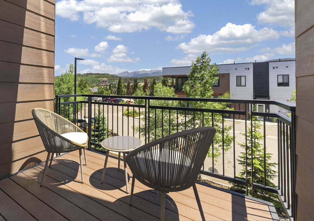 Step onto your private balcony and unwind in modern seating while taking in mountain and neighborhood views under bright skies—a peaceful retreat awaits.