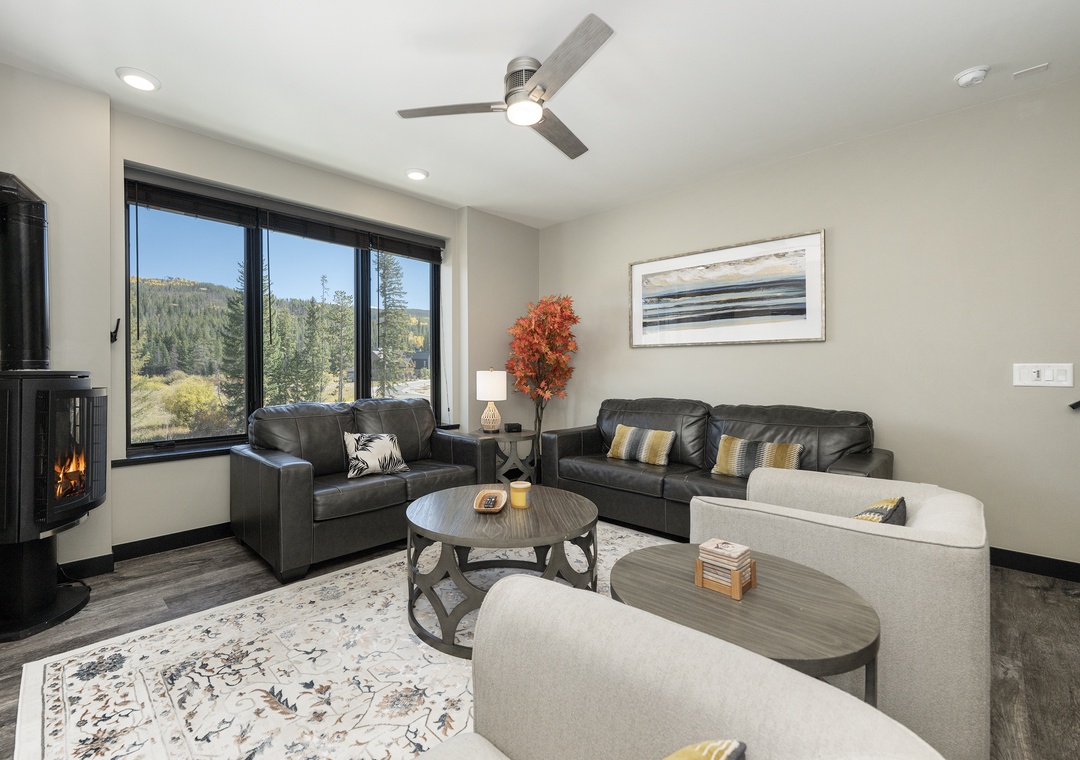 Unwind in your inviting living space with plush leather seating, cozy fireplace, and stunning mountain views through expansive windows.