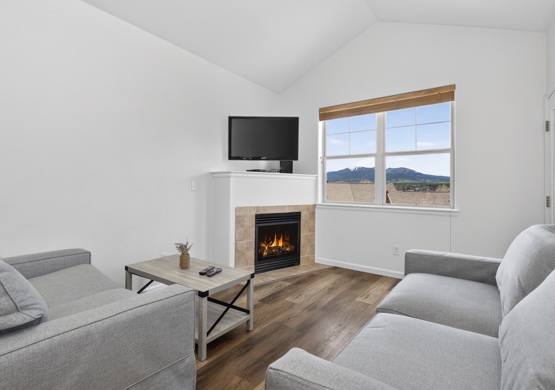 Unwind in your bright living room with vaulted ceilings, a warm fireplace, and stunning mountain views framed by large windows.