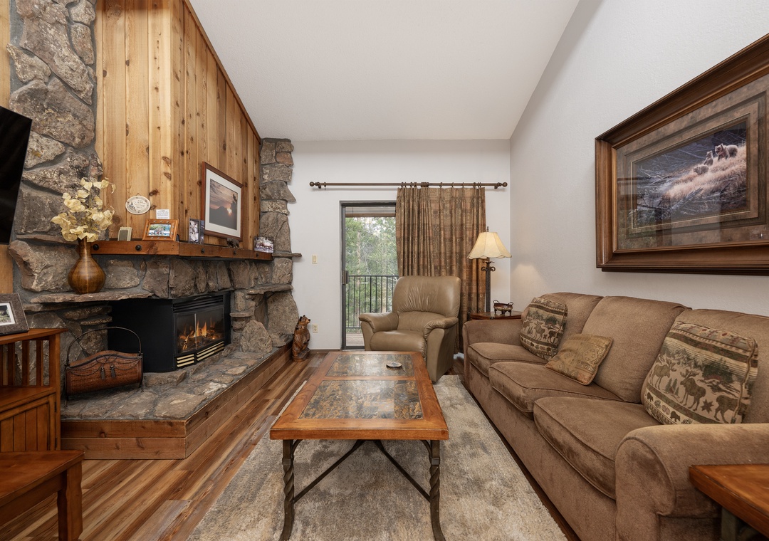 Relax by your stone fireplace while enjoying mountain views from your private balcony in this cozy living space.