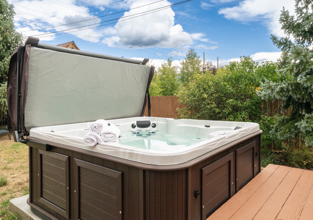 Slip into your private hot tub oasis, complete with fluffy towels, surrounded by lush greenery for ultimate relaxation.