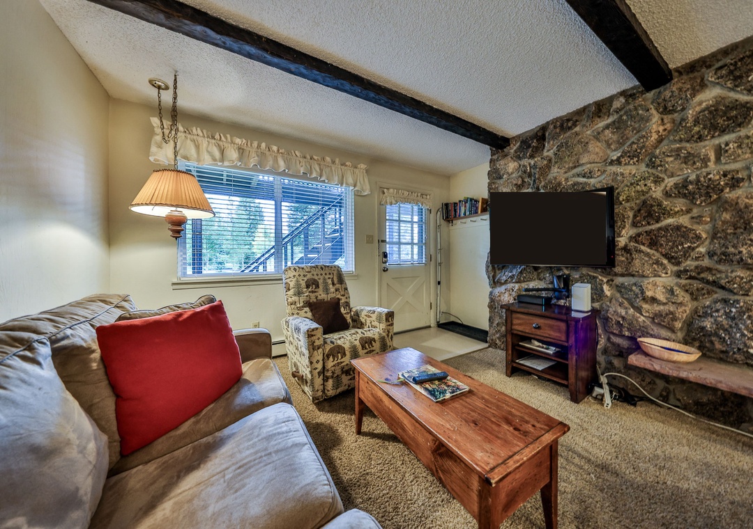 Cozy up in your rustic living room with exposed stone walls, plush seating, and warm wood accents creating the perfect mountain retreat atmosphere.