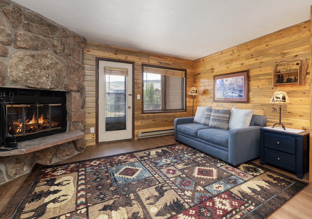 Cozy up by the crackling stone fireplace at 564 SilverCreek Inn in this rustic living room, where warm wood walls and mountain charm create the perfect retreat.