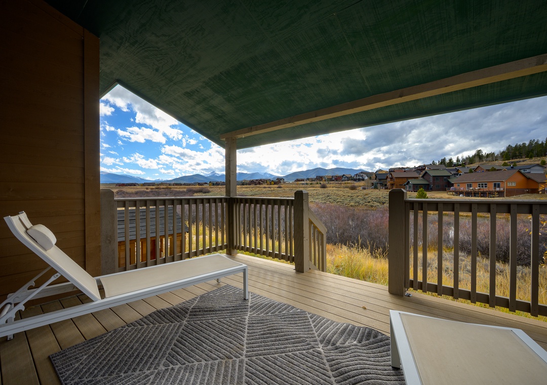 Covered deck with mountain views and open grasslands framing the property's natural setting—ideal for outdoor relaxation in this secluded retreat.
