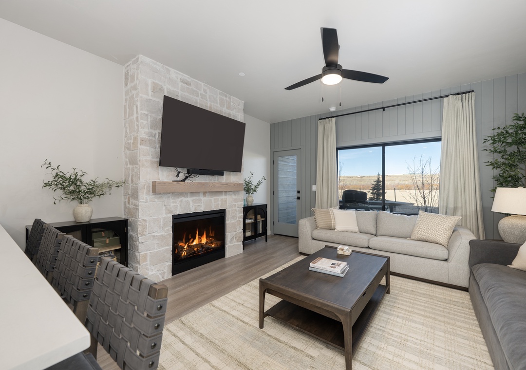 Unwind in your cozy living room where a crackling fireplace meets modern comfort, complete with plush seating and serene views.