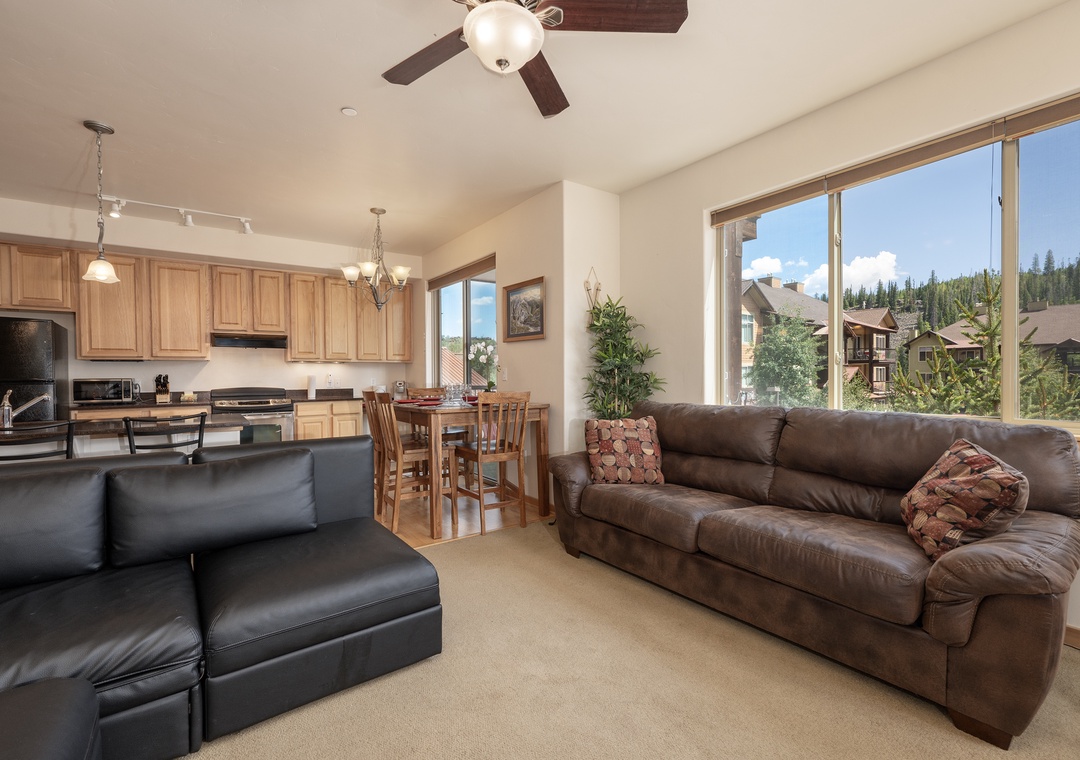 Relax in your spacious living room with leather seating while enjoying stunning mountain views through oversized windows.