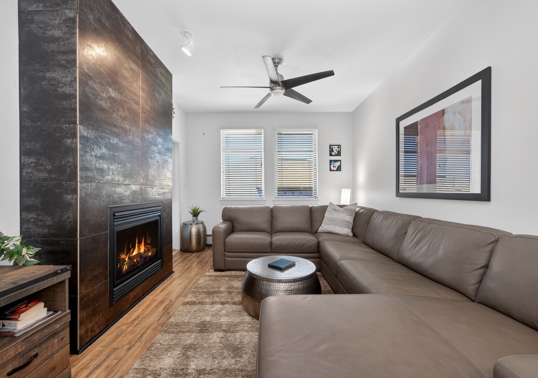 Sink into plush leather seating and feel the warmth of the fireplace glow across this bright, modern living space with vaulted ceilings and natural light.