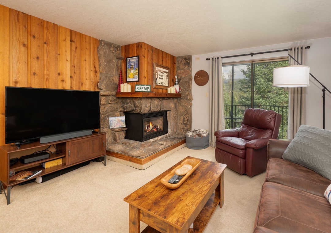 Cozy up by your stone fireplace in this warm living room with leather seating and mountain views through the balcony doors.