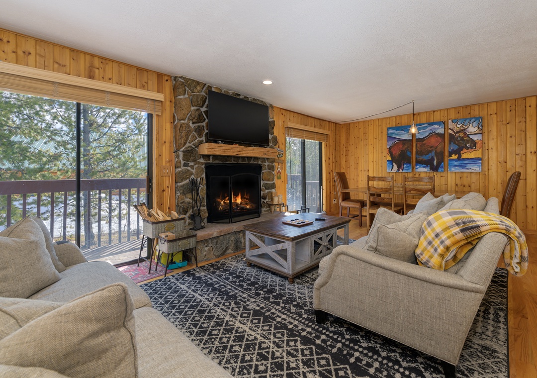 Cozy up in your rustic living room at 1126 Western Road where warm wood surrounds you, a stone fireplace crackles, and your private balcony offers peaceful views.
