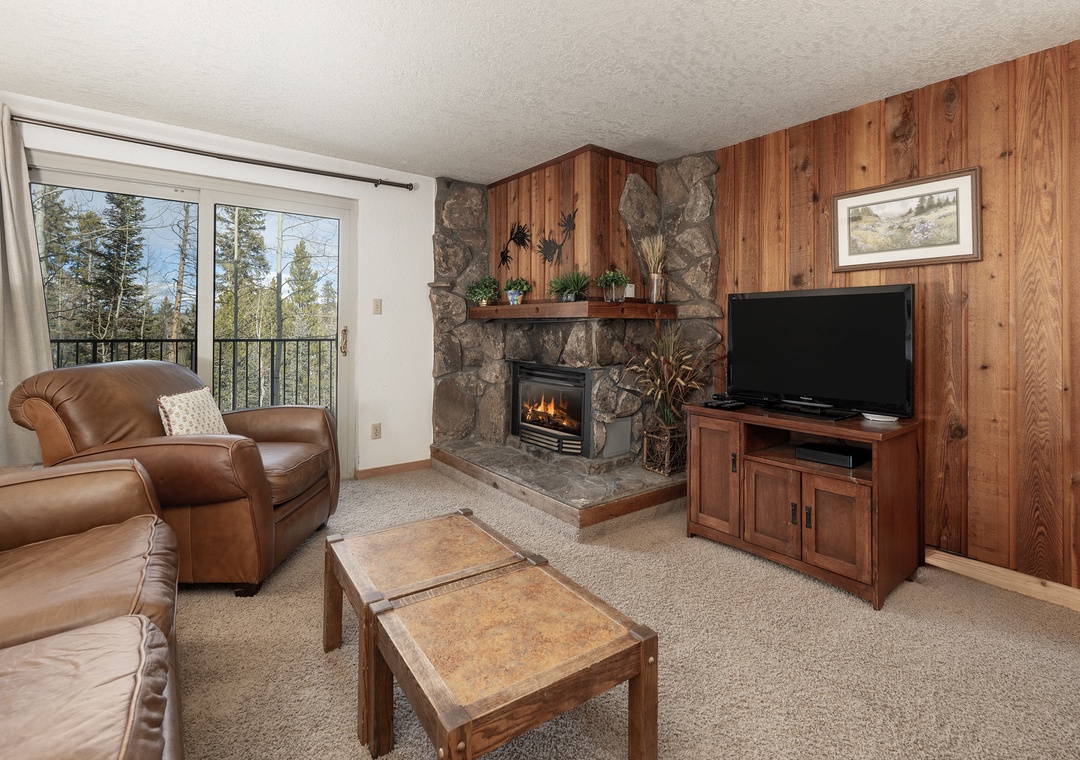 Cozy up by your crackling fireplace while watching TV, surrounded by rustic wood paneling and mountain views from your private balcony.