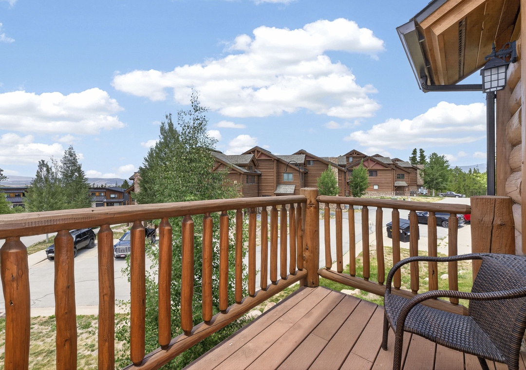 A scenic mountain property surrounded by trees and neighboring buildings, with parking visible below. The log cabin-style architecture adds rustic charm to this peaceful setting.