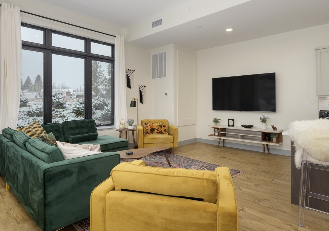 Sink into plush emerald velvet sofas while watching your favorite shows on the wall-mounted TV in this stylish living space.