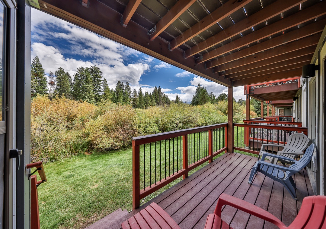 Relax on your private deck overlooking serene forest views, where morning coffee feels perfect under exposed beams.