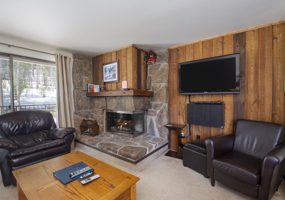 Settle into plush leather seating by your crackling stone fireplace, where warm wood paneling creates the perfect mountain retreat atmosphere.