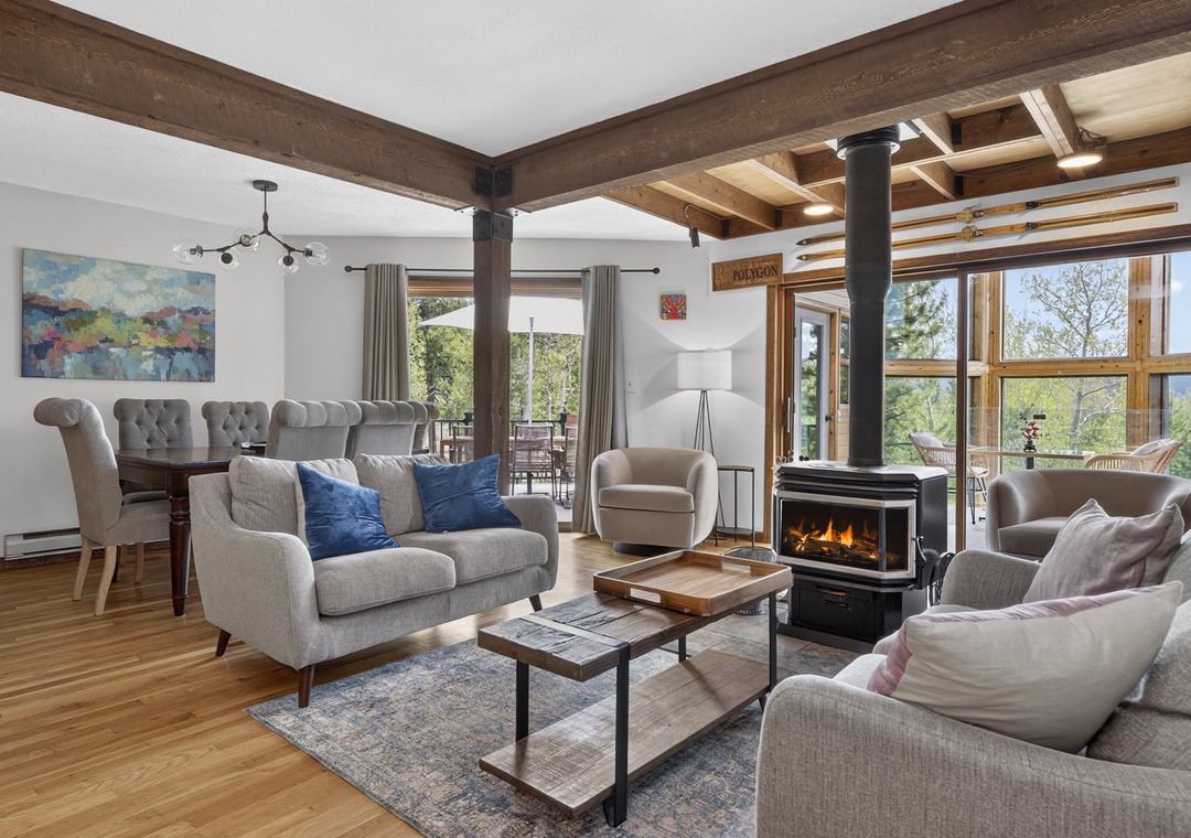 Picture yourself unwinding on the plush sofas, warmed by the fireplace as natural light streams through expansive windows framing stunning mountain and forest views—your perfect retreat awaits.