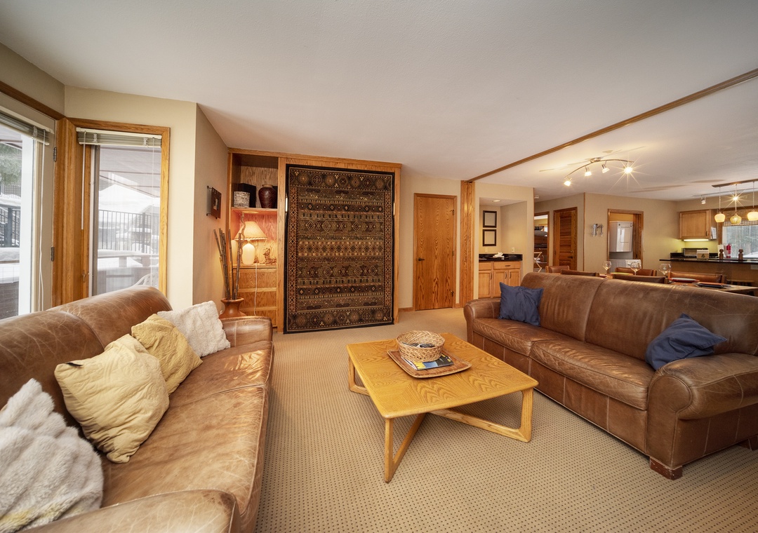 Relax in your spacious living room with rich leather sofas and warm wood accents creating the perfect mountain retreat atmosphere.