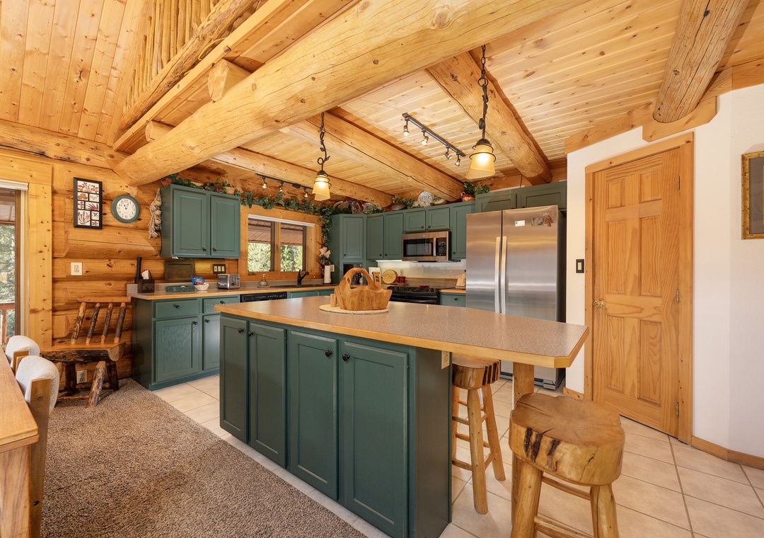 Step into your fully-equipped mountain kitchen with rustic beams, sage cabinetry, and stainless appliances—perfect for creating memorable meals together.