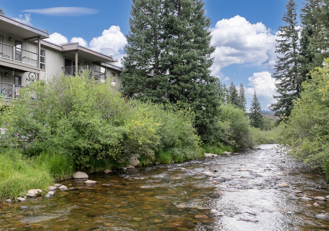 This vacation rental property borders a scenic riverside location with lush evergreens and natural mountain surroundings offering year-round outdoor appeal.