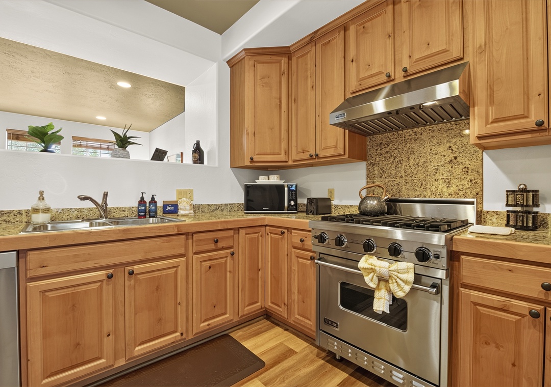 Your fully equipped kitchen features warm wood cabinetry, granite counters, and professional-grade appliances—including a Viking range with six burners—ready for everything from quick breakfasts to gourmet meals.