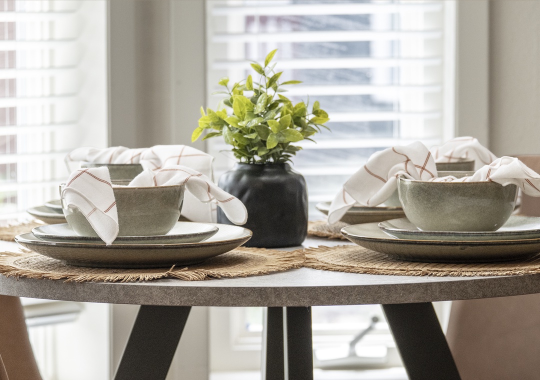 Settle in for a relaxed meal at your thoughtfully set table, complete with modern dinnerware and fresh greenery. Natural light pours through the windows, creating a warm and inviting space for your morning coffee or evening dining.