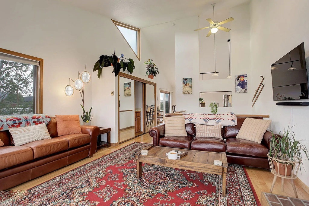 Sink into rich leather sofas surrounded by lush plants and eclectic art in this bright, bohemian living space designed for relaxation.