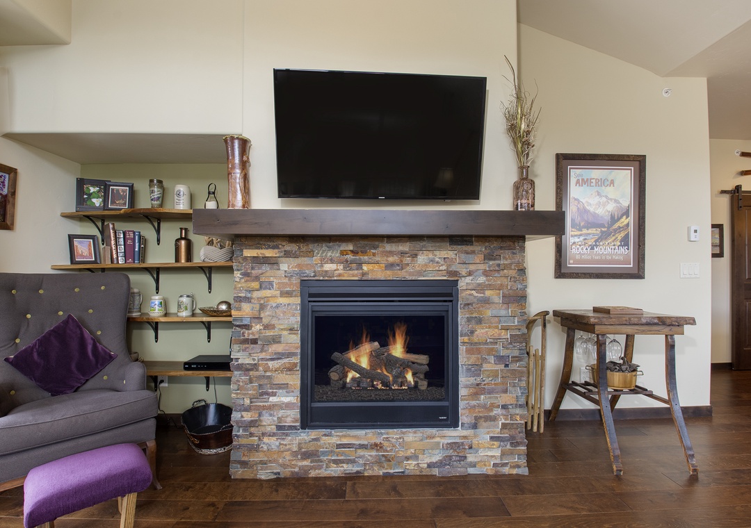 Cozy up by your crackling stone fireplace with mountain views on the wall-mounted TV above the rustic mantel.