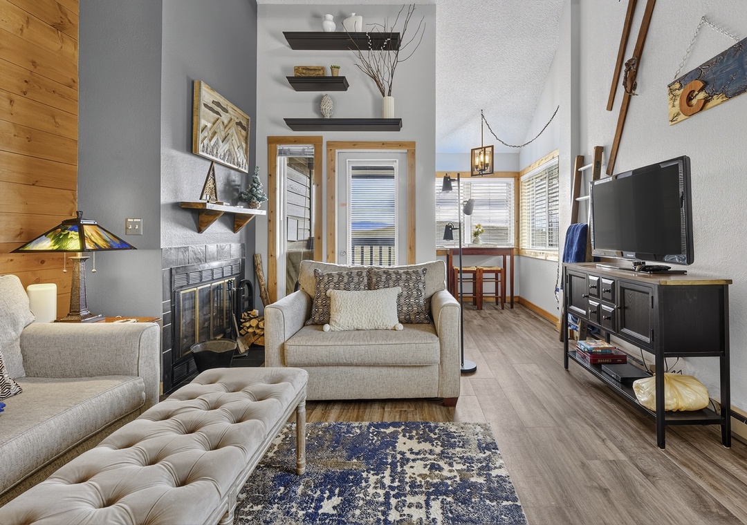 Unwind in your cozy mountain retreat with vaulted ceilings, natural light streaming through tall windows, and a warm fireplace perfect for après-ski relaxation.