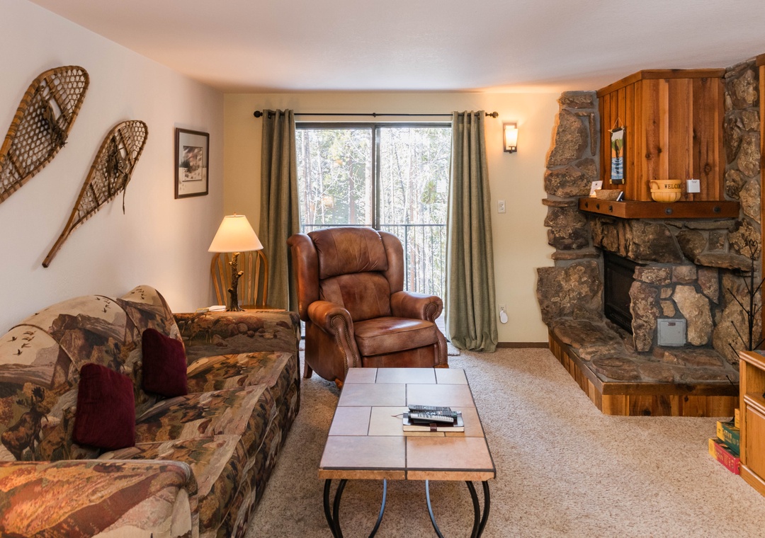 Cozy up by your stone fireplace with woodland views through large windows, perfect for relaxing evenings.