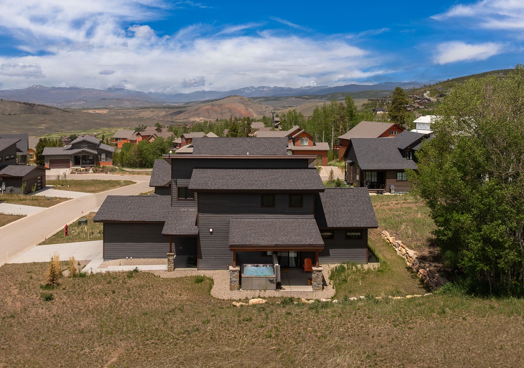 Expansive mountain property nestled in a quiet residential neighborhood, offering sweeping views of distant peaks and open Colorado terrain. The property features modern architecture with stone and wood accents.