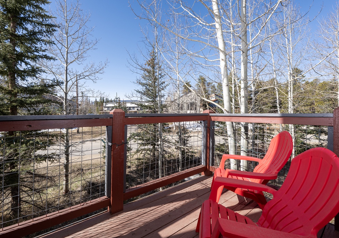 Relax in vibrant red Adirondack chairs on your private deck, surrounded by towering aspens and peaceful mountain views.
