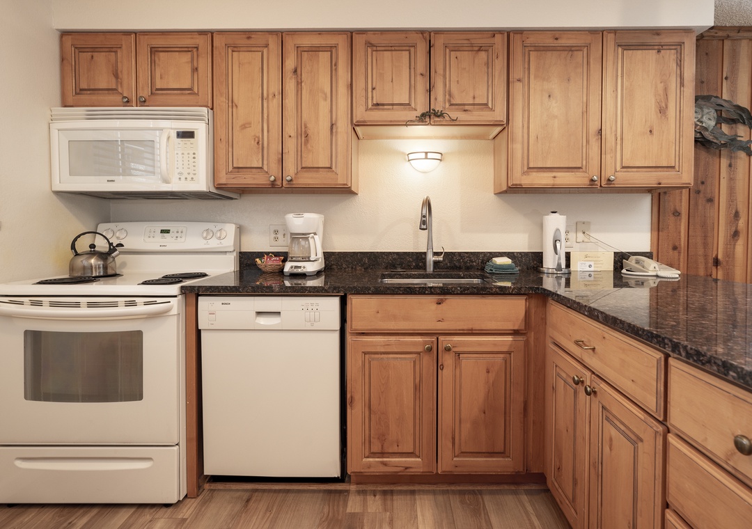 Your fully equipped kitchen awaits with warm wood cabinets, granite counters, and modern appliances to create memorable meals during your stay.