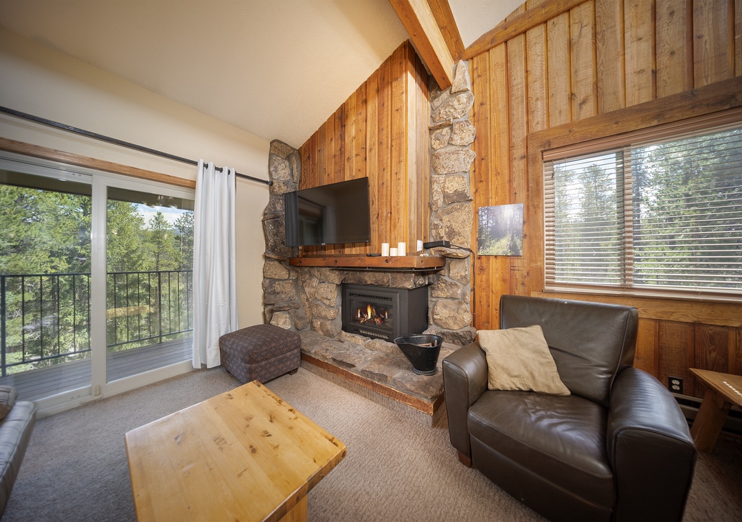 Cozy up by your crackling stone fireplace with forest views through the sliding doors.