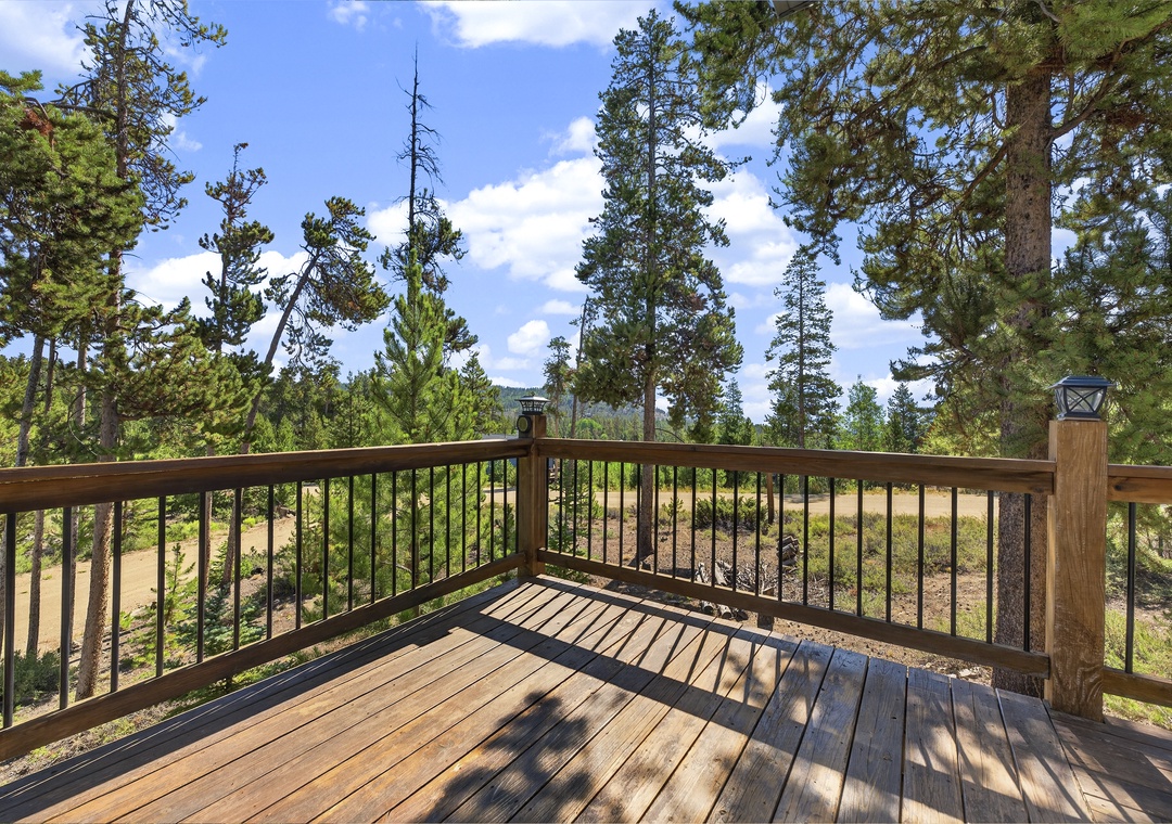 This spacious wooden deck offers a peaceful setting surrounded by tall pines and natural scenery—an ideal spot for your morning coffee or evening relaxation under open skies.