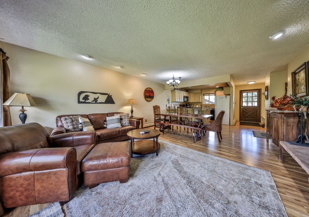 Relax in your spacious open-concept living area featuring rich leather seating, warm wood floors, and mountain cabin charm.