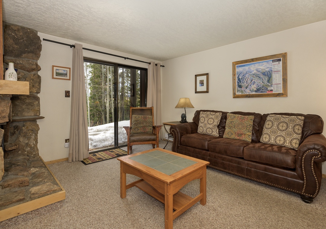Cozy up in your welcoming living room featuring a stone fireplace and plush leather sofa, perfect for relaxing after mountain adventures.