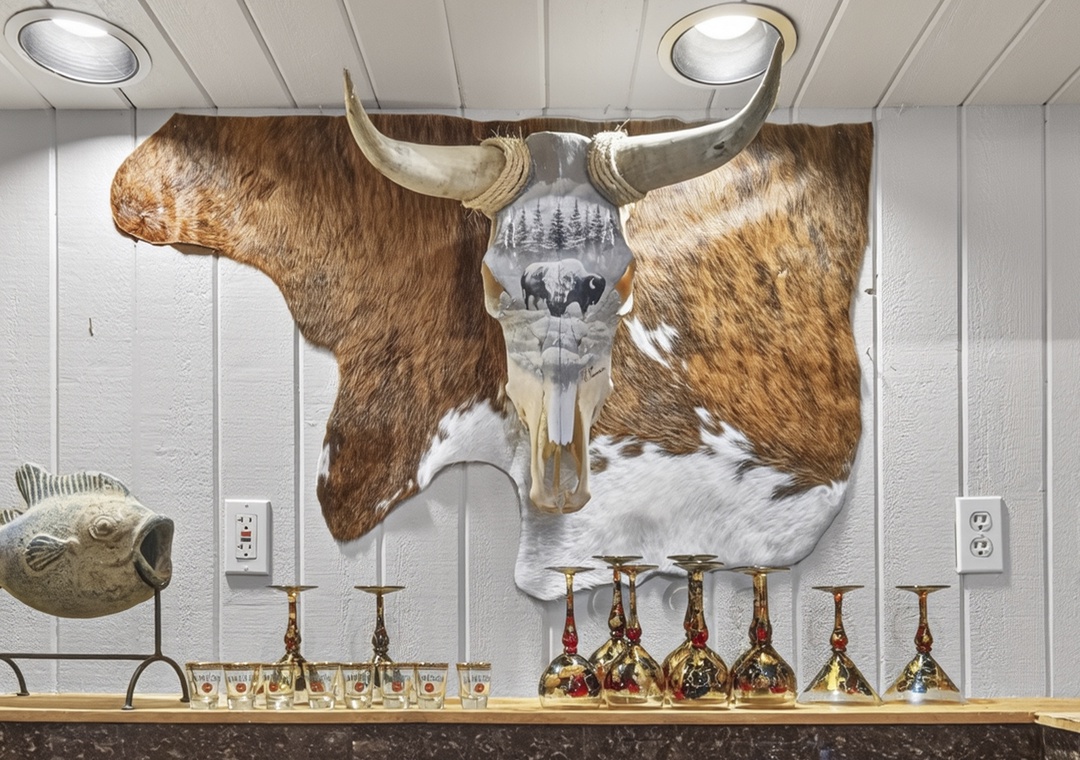 Unique rustic decor welcomes you with a striking longhorn hide accent and elegant barware display, blending mountain charm with distinctive style.