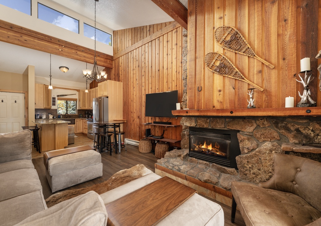 Cozy up by your crackling stone fireplace while snowshoes hang overhead, creating the perfect mountain retreat atmosphere for your alpine getaway.