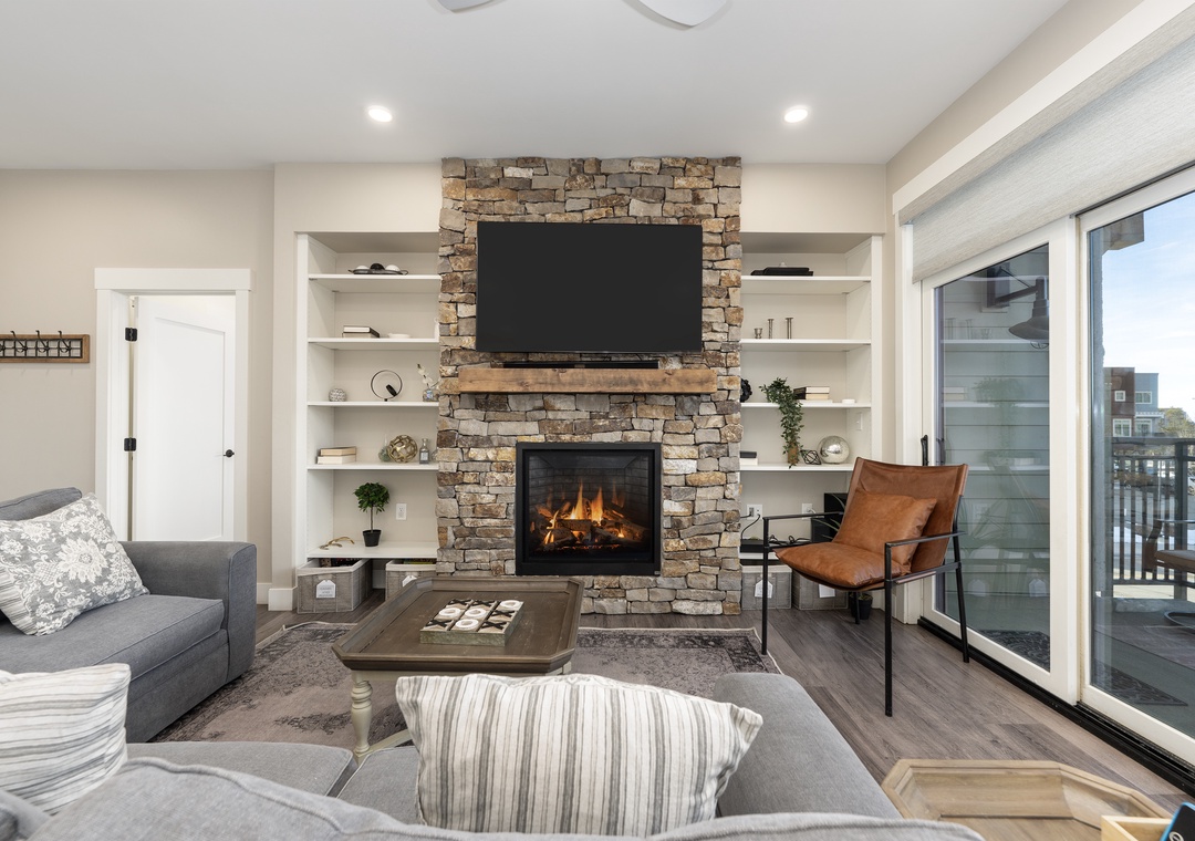 Unwind in your stylish living room where a crackling stone fireplace and cozy seating create the perfect atmosphere for relaxation.