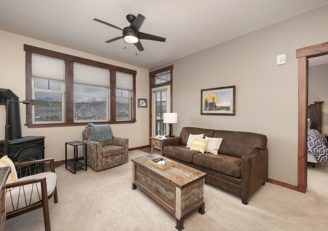 Relax in this cozy living room with leather sofa, mountain views, and rustic touches that create the perfect mountain retreat atmosphere.
