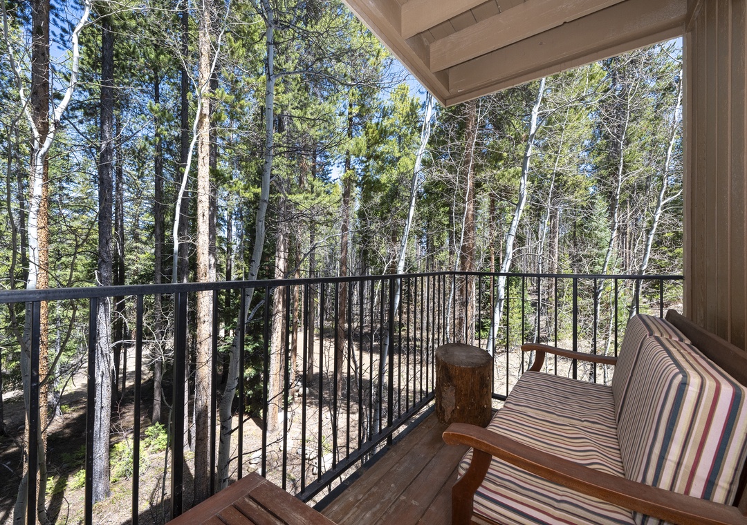 Relax on your private balcony surrounded by towering forest trees, where the peaceful woodland setting creates the perfect retreat.