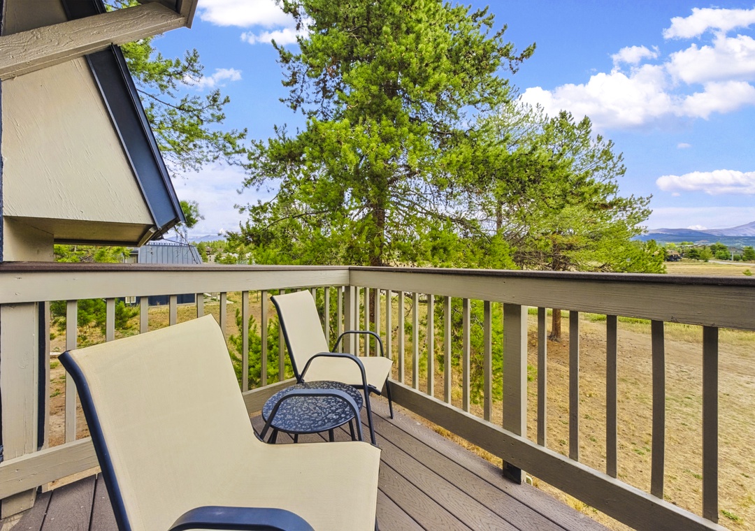 The exterior of the property is framed by lush trees and offers a scenic mountain backdrop in the distance.