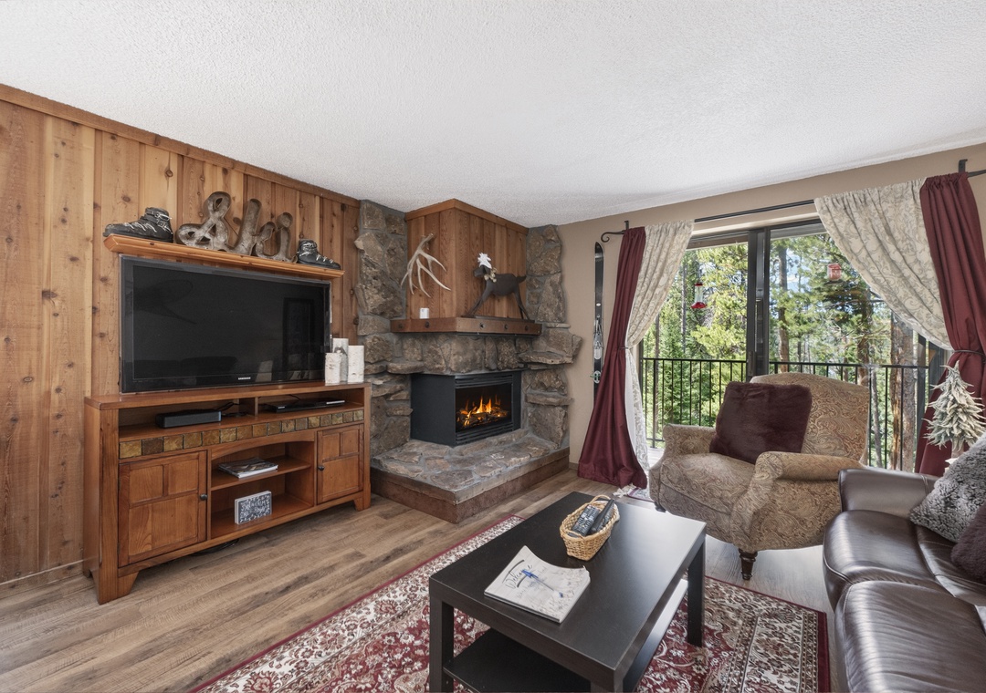 Cozy up in your living room with a crackling stone fireplace, large TV, and comfortable seating overlooking the treetops.