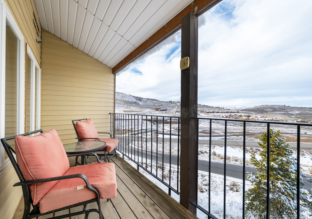 Relax on your private covered balcony at Mountainside Unit B-8 with panoramic winter mountain views and comfortable seating for morning coffee or evening unwind.